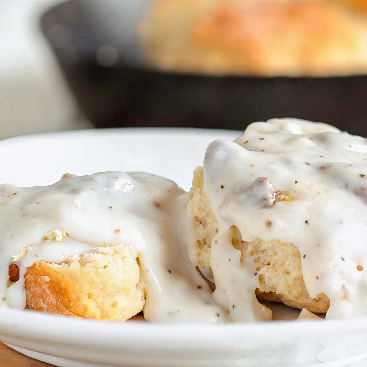 Close up of biscuits and sausage gravy on white plate.