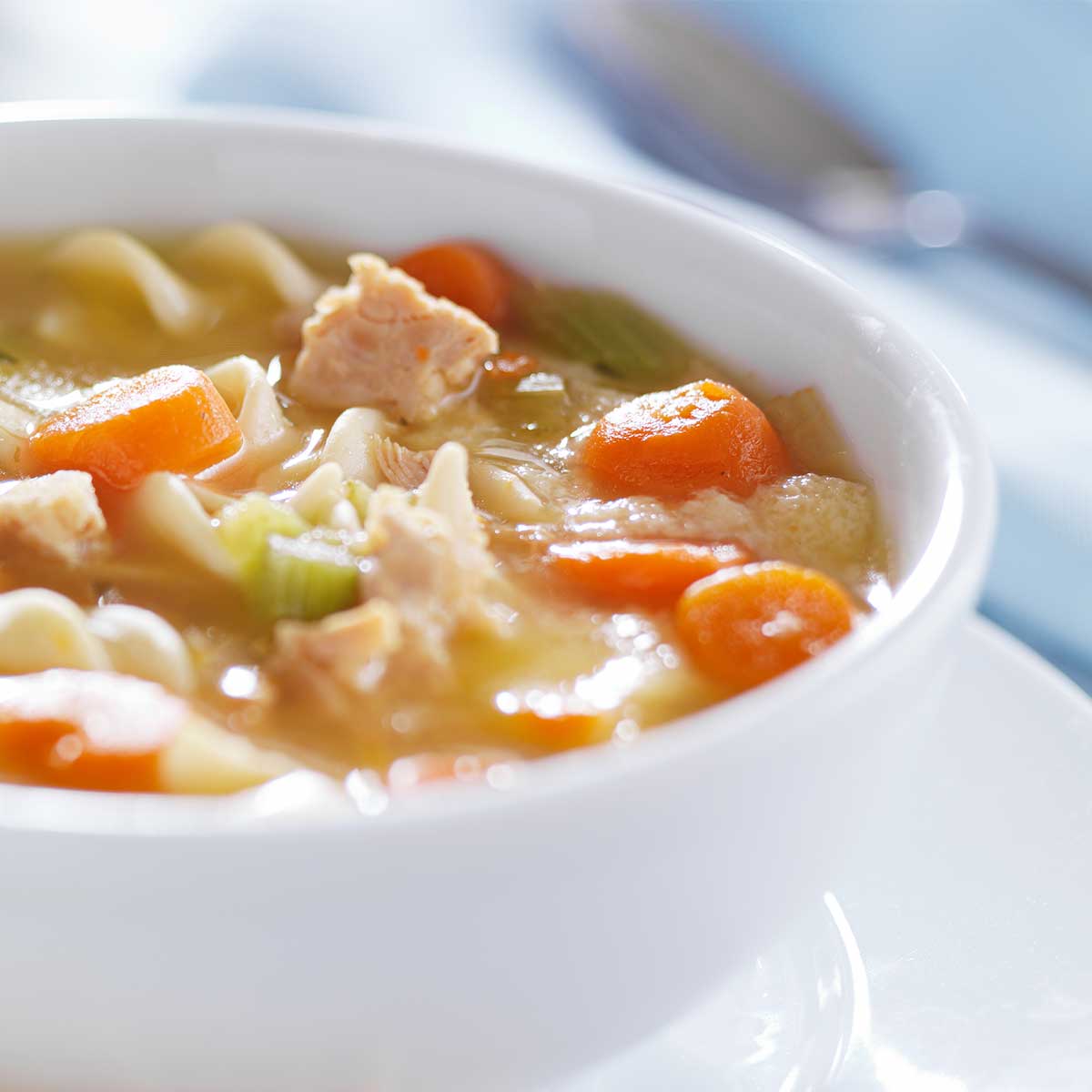Hearty chicken noodle soup in white bowl.