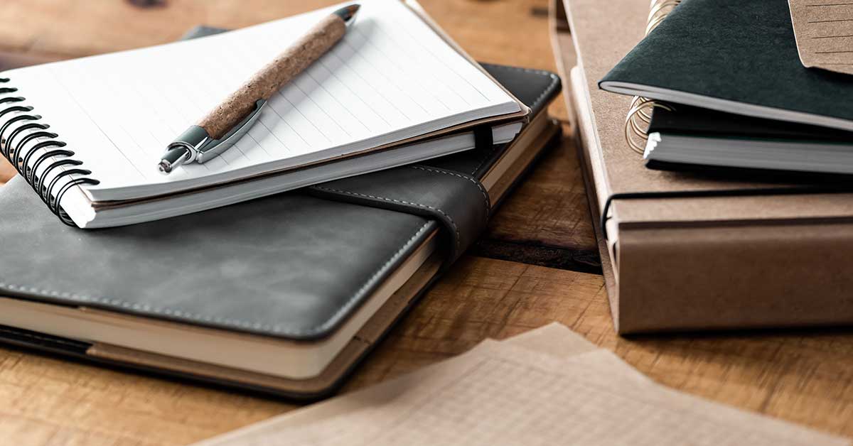 Planners and writing supplies on wood table.