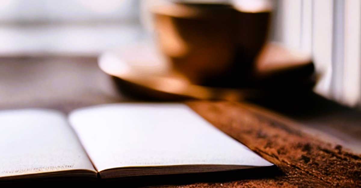 Open blank journal on very rough wood table with coffee mug in background.