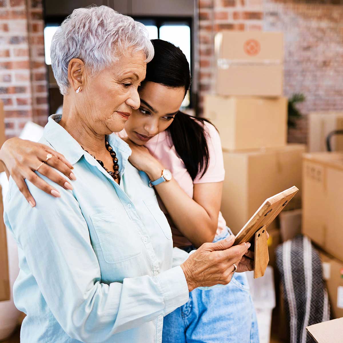 Older woman and younger woman decluttering sentimental items in preparation for downsizing.