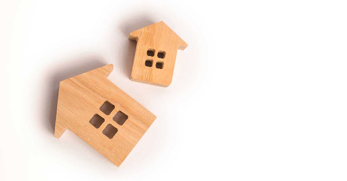 Two wooden block houses on white background representing decluttering and downsizing.