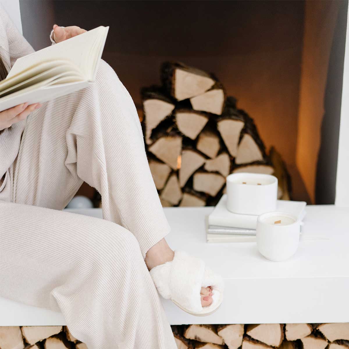 Sunday reset aesthetic of woman wearing comfortable and soft clothing while relaxing on white bench and reading.