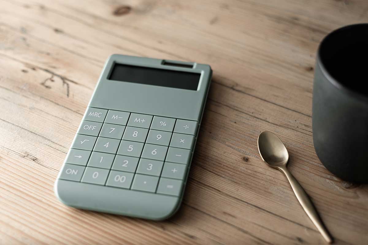 Calculator and coffee mug on wood table.