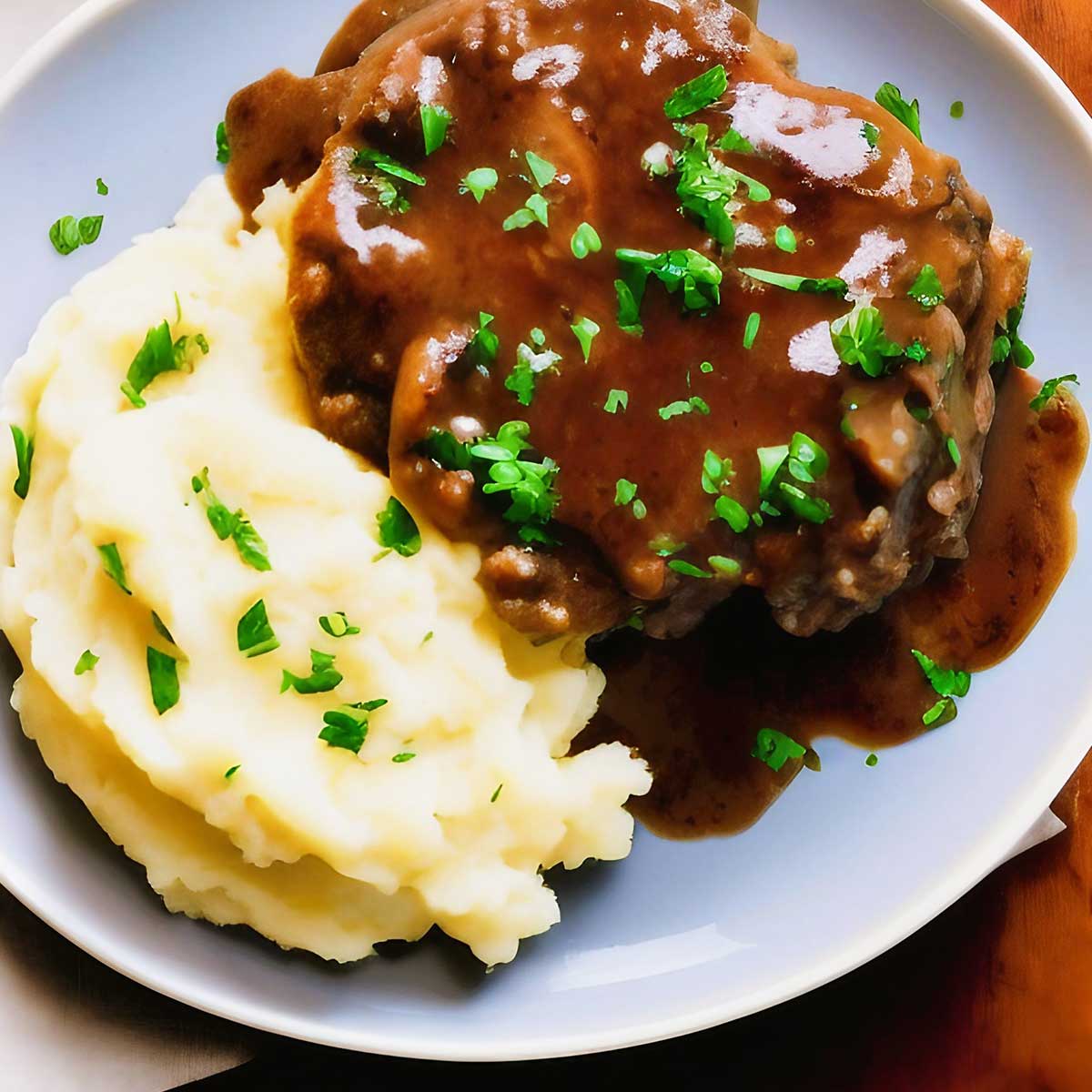 White plate with Salisbury steak and mashed potatoes.