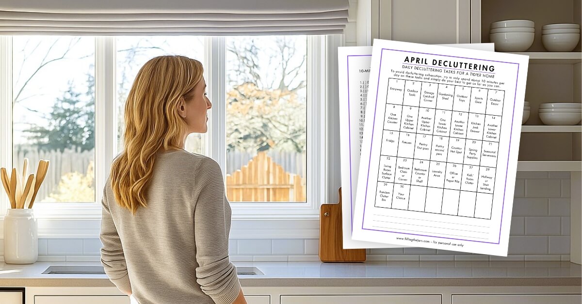 A woman with long blond hair stands in a bright kitchen looking out the window, with an April declutter calendar mockup beside her in the foreground.