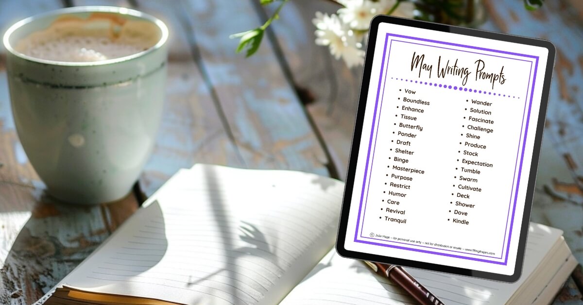 A cozy flat lay of a spring morning writing scene featuring a mug of coffee, an open lined journal, and a tablet displaying a list of May one word writing prompts.