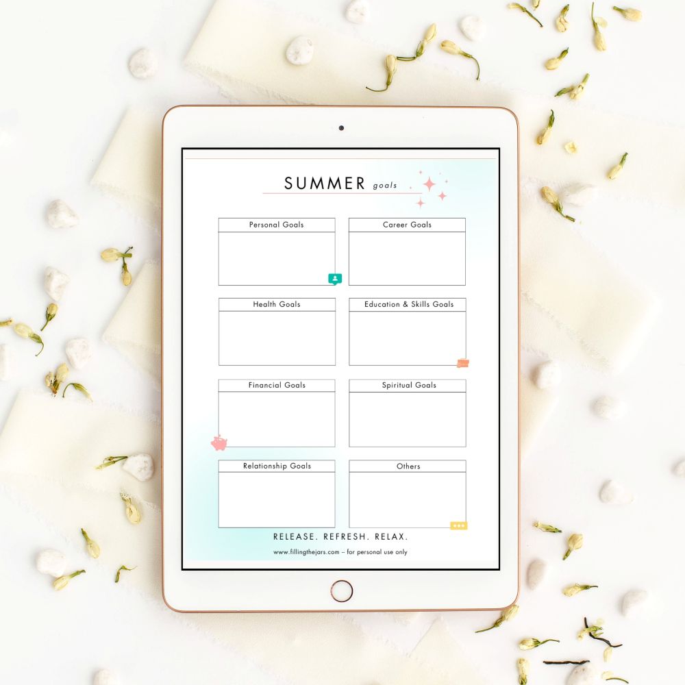 Summer goals page from Filling the Jars' Simple Summer planner shown on an ipad screen over a flatlay backdrop of flower buds and pebbles.